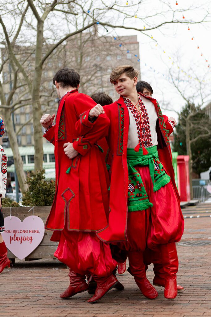 Yunist Ukrainian Dance Group members performing in vibrant red traditional costumes outdoors.