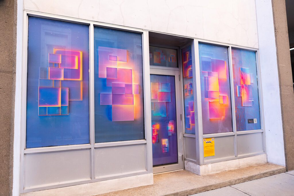 LUMINA installation 'The Chromatic Visitor' by Max Van Lorimer, featuring vibrant geometric patterns on a storefront facade.