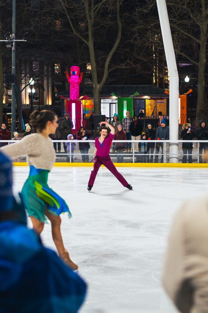 Ice dancers performing at "Ice Dance International" with colorful lights and spectators in the background.