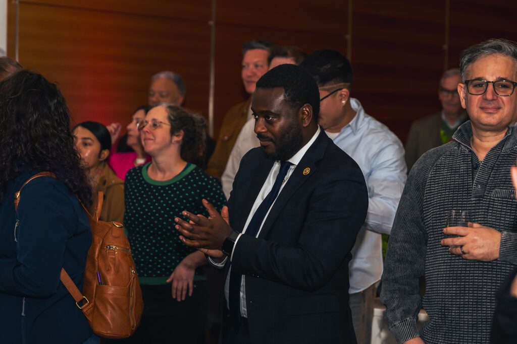 Rhode Island Congressman Gabe Amo attends LUMINA, clapping among a group of people.