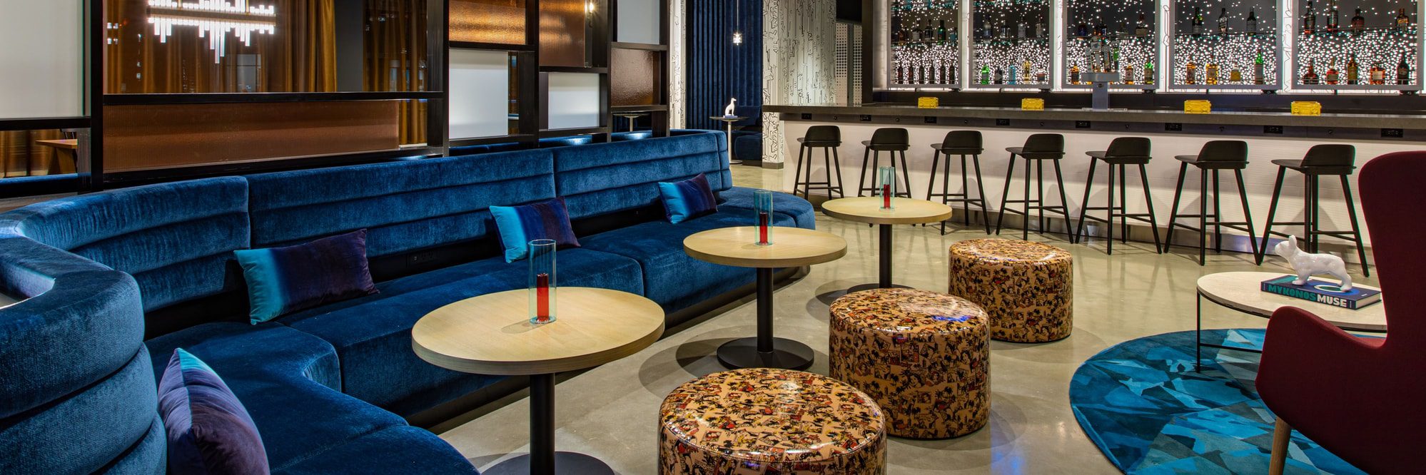 W XYZ Bar at Aloft Providence RI with modern blue velvet seating, sleek bar stools, and illuminated liquor display, creating a stylish and inviting lounge atmosphere.